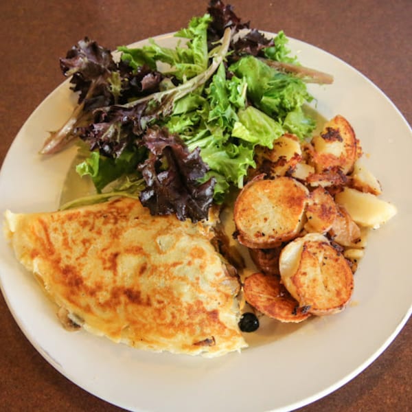 Savory crepe with a side of crispy home fries and fresh mixed greens from Sterling Café.